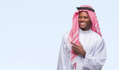 Geleneksel keffiyeh izole arka neşeli bir gülümseme ile el ve parmak kadar kameraya bakarak yüzündeki mutlu ve doğal ifade ile yan ile işaret yüz üzerinde giyen genç Arapça Afrika adam.