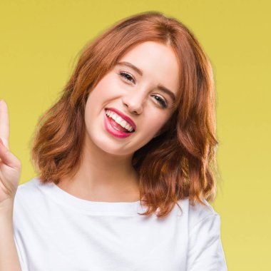 Genç güzel kadın mutlu yüz zafer işareti yaparken kameraya göz kırpıyor ile gülümseyen izole arka plan yüzünden. İki numaralı.