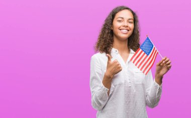 Ok işareti, başparmak ile parmak, mükemmel işareti yapıyor kocaman bir gülümseme ile Estates Amerika bayrağı mutlu tutan genç İspanyol kadın