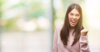 Öfkeli ve sinirli sinirli ve öfke ile bağırarak süre öfkeli yumruk yükselterek bir kazak giyen genç güzel İspanyol kadın. Öfke ve agresif kavramı.