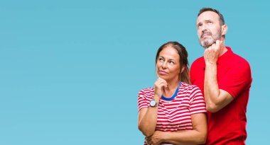 Orta yaş İspanyol çift çene düşünme hakkında soru, dalgın ifade üzerine el ile izole arka plan üzerinde aşık. Düşünceli yüzüyle gülümsüyor. Şüphe kavramı.