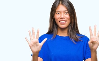 Genç Asyalı kadın gösterilen ve parmakları ile işaret izole arka plan üzerinde numara 9 kendinden emin ve mutlu gülümseyerek süre.