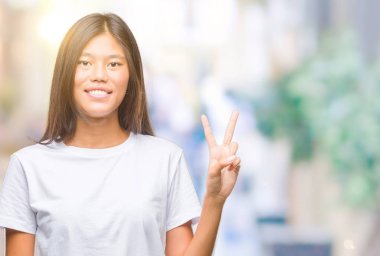 Genç Asyalı kadın gösterilen ve parmakları ile işaret izole arka plan üzerinde ikincisi ise kendinden emin ve mutlu gülümseyerek.