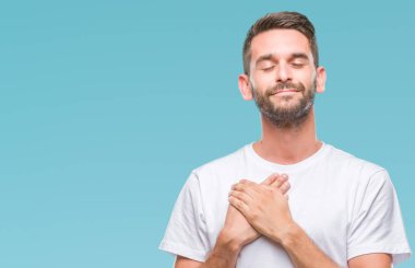 Yakışıklı delikanlı ile gülümseyen izole arka plan üzerinde kapalı gözler ve yüzünde minnettar jest ile göğüs üzerinde eller. Sağlık kavramı.