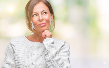 Üzerinde kış kazak giyen orta yaş üst düzey İspanyol kadın arka plan çene düşünme hakkında soru, dalgın ifade üzerine el ile izole. Düşünceli yüzüyle gülümsüyor. Şüphe kavramı.