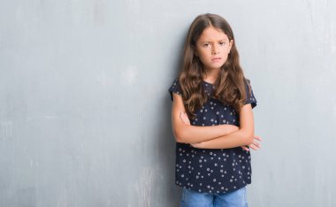 Grunge gri duvar şüpheci ve sinir, onaylamayan ifade yüz çapraz kolları olan genç İspanyol çocuk. Negatif kişi.