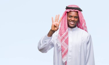 Geleneksel keffiyeh gösterilen ve parmakları ile işaret izole arka plan üzerinde giyen genç Arapça Afrika adam kendinden emin ve mutlu gülümseyerek süre dört numara.