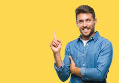 Kameraya bakarak yan el ve parmak ile işaret eden genç yakışıklı adam yüzünde kocaman bir gülümseme ile izole arka plan üzerinde.