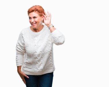 Bir işitme söylenti ya da dedikodu için dinleme kulak üzerinde el ile gülümseyen izole arka plan üzerinde kış kazak giyen Atrractive üst düzey beyaz Kızıl saçlı kadın. Sağırlık kavramı.