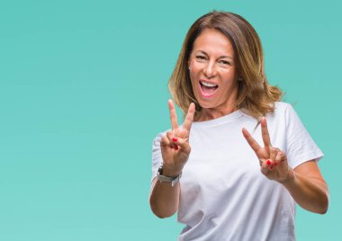Orta yaş üst düzey İspanyol kadın parmaklarını zafer işareti yaparken gösterilen kamera seyir gülümseyen izole arka plan yüzünden. İki numaralı.