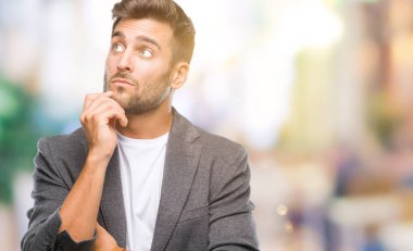 Genç yakışıklı iş adamı çene düşünme hakkında soru, dalgın ifade üzerine el ile izole arka plan üzerinde. Düşünceli yüzüyle gülümsüyor. Şüphe kavramı.