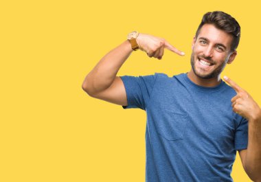 Tecrit edilmiş, güler yüzlü, kendine güvenen, parmaklarını, dişlerini ve ağzını gösteren genç yakışıklı bir adam. Sağlık kavramı.