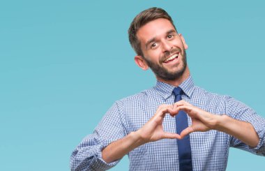Genç yakışıklı iş adamı aşık kalp simgesi ve elleriyle şekil gösteren gülümseyen izole arka plan üzerinde. Romantik kavramı.