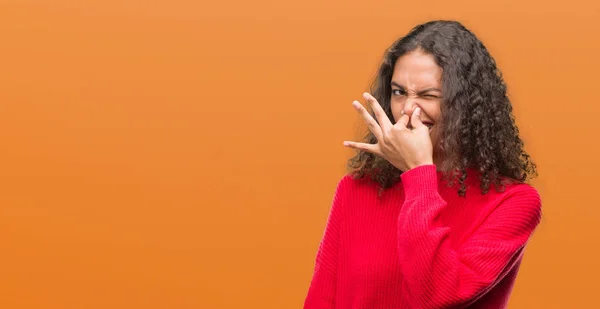 穿着红色毛衣的年轻西班牙女人闻到了臭味和恶心的气味 鼻子上握着手指的气息 坏气味概念 — 图库照片