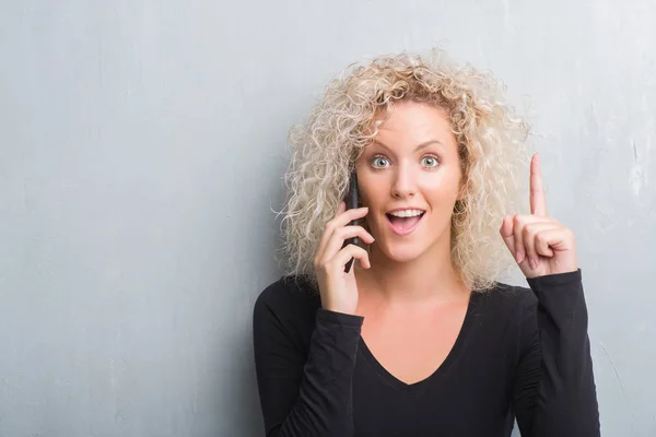 Joven Rubia Sobre Fondo Gris Grunge Hablando Por Teléfono Sorprendida — Foto de Stock