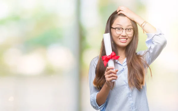 若いアジア女性の頭の上の手を強調した分離の背景上の学位を保持 恥と驚きの顔でショックを受けて怒っているとイライラします 恐怖と動揺の間違い — ストック写真