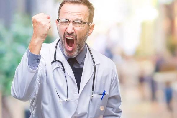 中年老年医生身穿医疗制服隔离背景愤怒和疯狂的举起拳头沮丧和愤怒 而愤怒的呼喊 愤怒和侵略性概念 — 图库照片
