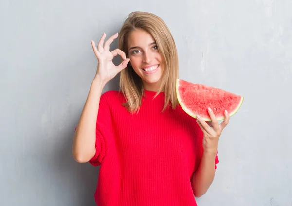 優秀なシンボルの指で サインをしてスイカを食べるグランジ灰色の壁に美しい若い女性 — ストック写真