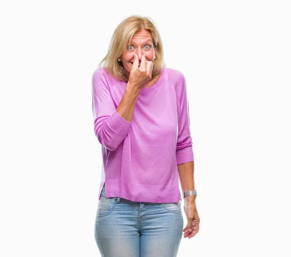 中年金发女人在与世隔绝的背景下闻到一些臭味和恶心 难以忍受的气味 用手指在鼻子上屏住呼吸 坏气味概念 — 图库照片