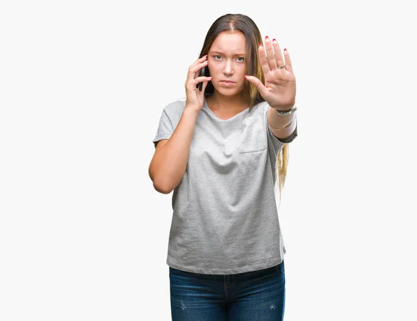 分離の背景にスマート フォンで話している若い美しい白人女性が防衛ジェスチャー 深刻な自信を持って式に一時停止の標識をやって手を開いてください — ストック写真