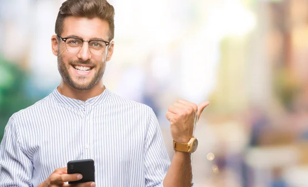 年轻英俊的人发短信使用智能手机在孤立的背景指向和显示与拇指面带笑脸微笑 — 图库照片