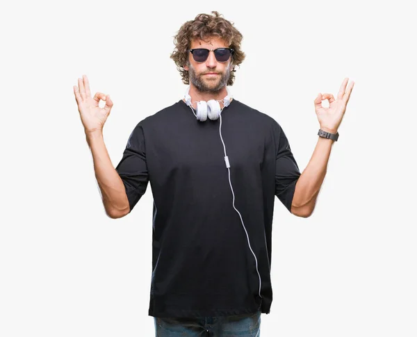 英俊的拉美裔男子听音乐戴着耳机在孤立的背景下放松和微笑闭上眼睛做冥想手势用手指 瑜伽理念 — 图库照片
