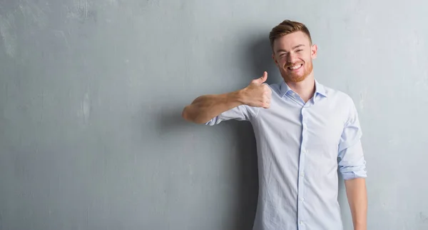 Young Redhead Business Man Grey Grunge Wall Doing Happy Thumbs — Stock Photo, Image