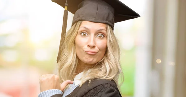 Young graduate woman proud, excited and arrogant, pointing with victory face