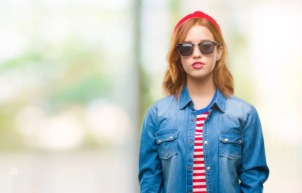 Young beautiful woman over isolated background wearing sunglasses with serious expression on face. Simple and natural looking at the camera.