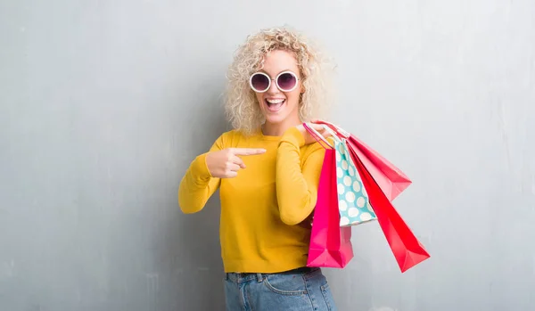 Jovem Loira Sobre Grunge Fundo Cinza Segurando Sacos Compras Vendas — Fotografia de Stock