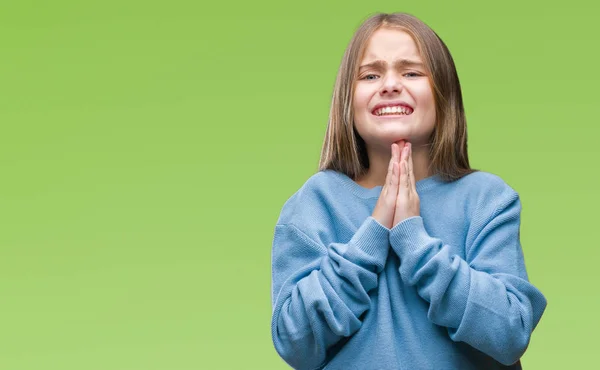 Young beautiful girl wearing winter sweater over isolated background begging and praying with hands together with hope expression on face very emotional and worried. Asking for forgiveness. Religion concept.