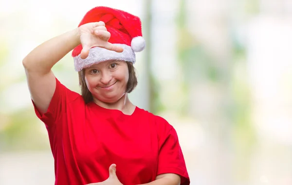 笑顔の幸せそうな顔で指と手作りフレーム分離の背景にクリスマス帽子をかぶっているダウン症の若い大人の女性 創造性と写真のコンセプト — ストック写真