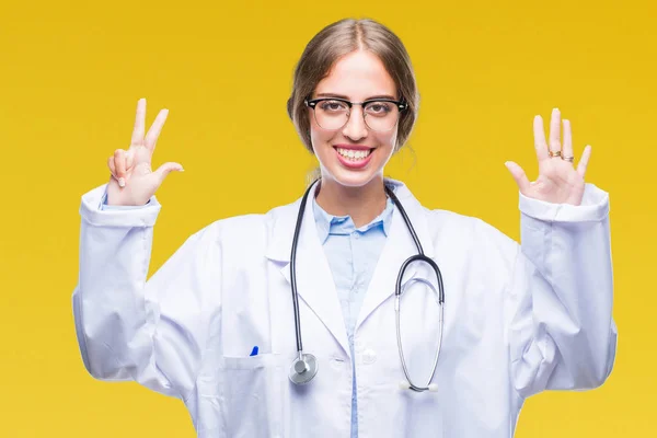 美丽的年轻金发碧眼的医生妇女穿着医疗制服在孤立的背景显示和手指指向八号 同时微笑着自信和快乐 — 图库照片