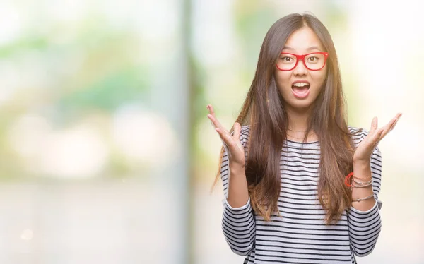 年轻的亚洲妇女戴着眼镜在孤立的背景下庆祝疯狂和惊讶的成功与手臂举起 睁开眼睛尖叫兴奋 赢家理念 — 图库照片