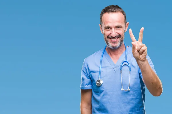 中年老人穿着医疗制服在孤立的背景显示和指向手指第二 而微笑着自信和快乐 — 图库照片
