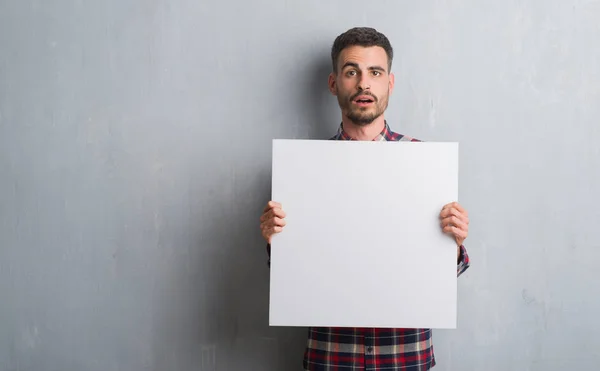 Young Adult Man Brick Wall Holding Banner Scared Shock Surprise — Stock Photo, Image