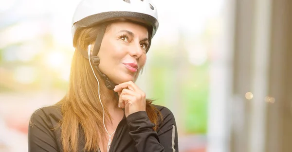 中年骑自行车的妇女用耳机思考和寻找表达怀疑和疑惑 — 图库照片