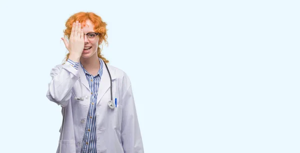 Młoda Ruda Kobieta Nosi Mundur Lekarz Obejmujące Jedno Oko Ręką — Zdjęcie stockowe