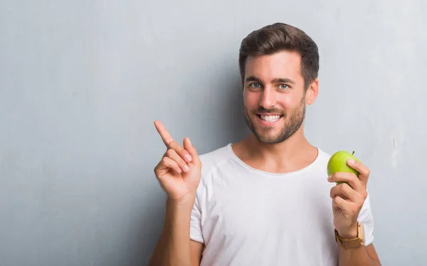 Schöner Junger Mann Über Grauer Grunge Wand Isst Grünen Apfel — Stockfoto
