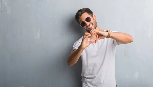 Joven Guapo Sobre Una Pared Grunge Gris Con Gafas Sol — Foto de Stock