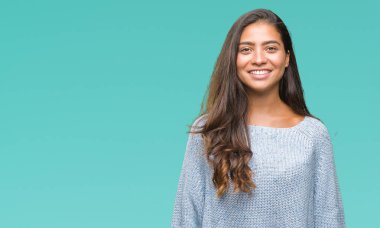 Yüzünde mutlu ve güzel bir gülümseme ile izole arka plan üzerinde kış kazak giyen genç güzel Arap kadın. Şanslı kişi.