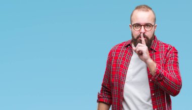 Dudaklarında parmak ile sessiz olmanı izole arka plan üzerinde gözlük takan Genç beyaz hipster adam. Sessizlik ve gizli kavramı.