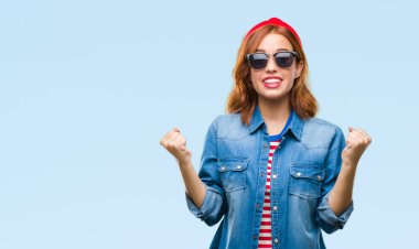 Genç güzel kadın kutluyor güneş gözlüğü takıyor izole arka plan yüzünden şaşırttı ve silah ile başarı için yükseltilmiş ve açık gözler hayrete düşürdü. Kazanan kavramı.