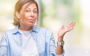 Orta yaş üst düzey İspanyol kadın izole arka plan clueless ve şaşkın bir ifadeyle kollar ve eller kaldırdı. Şüphe kavramı.