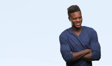 İzole arka plan mutlu yüz çapraz silah kameraya bakarak ile gülümseyen genç Afro-Amerikan adam. Olumlu bir kişi.