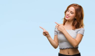 Gülümseyen ve iki elleri ve parmakları ile tarafına işaret kamera bakarak izole arka plan üzerinde genç güzel kadın.