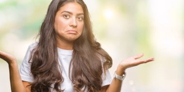 Genç güzel Arap kadın izole arka plan clueless ve şaşkın bir ifadeyle kollar ve eller kaldırdı. Şüphe kavramı.