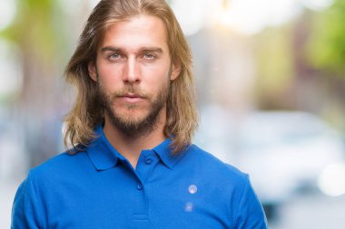 Yüzünde ciddi bir ifade ile izole arka plan üzerinde uzun saçlı Genç yakışıklı adam. Basit ve doğal kameraya bakıyor.