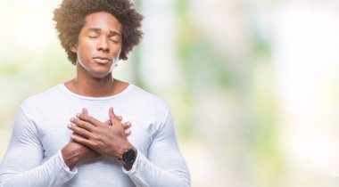 Afro Amerikalı adam ile gülümseyen izole arka plan üzerinde kapalı gözler ve yüzünde minnettar jest ile göğüs üzerinde eller. Sağlık kavramı.