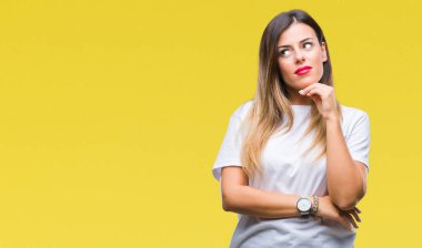 Genç güzel kadın rahat beyaz t-shirt üzerine arka plan ile ilgili soru, dalgın ifade düşünme çene yandan izole. Düşünceli yüzüyle gülümsüyor. Şüphe kavramı.